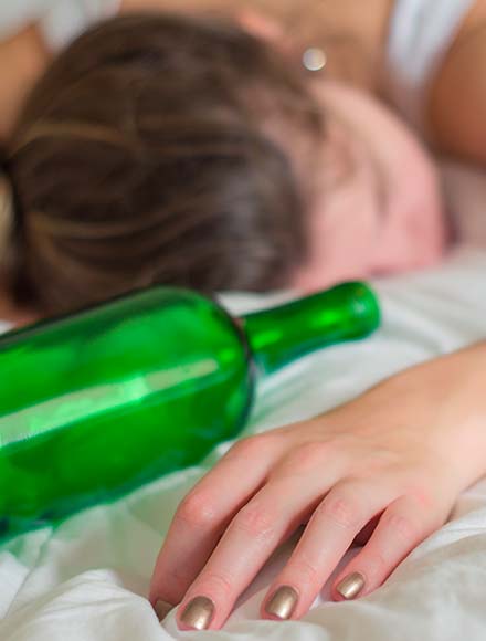 женщина лежит на кровати рядом с бутылкой вина