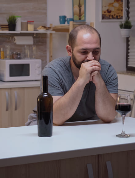 Мужчина сидит перед бутылкой вина