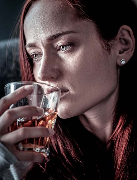 молодая девушка пьет алкоголь из стакана